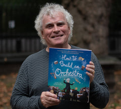 Sir Simon Rattle with the childrens' book How to Build an Orchestra